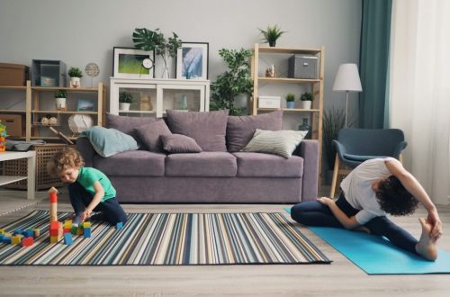 a woman and a child playing on a rug in a living room